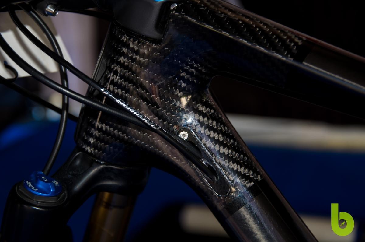 Es un secreto a voces que Mondraker, junto con su equipo profesional de mtb, está desarrollando una bici de doble suspensión para XC. Esta bici se encuentra a en la etapa final de desarrollo y, aunque aún puede sufrir algún cambio antes de salir al mercado, hemos tenido la suerte de fotografiar la Mondraker de Carlos Coloma de cerca y os traemos todos los detalles, componentes y peso.  El objetivo de Mondraker es conseguir una mountain bike con doble suspensión que pese menos de 9 kg y sea la referencia para el resto de fabricantes. Nosotros subimos a la báscula la bici de Carlos Coloma y aún le queda un poco para bajar de 9 kg, pero como decímos, no es la versión definitiva.   Mondraker XC doble suspensión Carlos Coloma  La Mondraker XC con doble suspensión de Carlos Coloma  Esta Mondraker de estética robusta pero de construcción ligera mantiene la estética de la marca con su potencia integrada y la continuidad en línea de su tubo superior hasta la rueda trasera. Podemos decir que el triangulo delantero es casi idéntido al del la actual Podium, pero es el sistema de suspensión trasera donde reside el potencial de esta mountain bike.  Mondraker XC doble suspensión Carlos Coloma  Durante la Copa del Mundo de Nove Mesto ya pudimos ver algunas imágenes de esta bici, pero ha sido durante el Campeonato de España cuando nos hemos acercado a verla en detalle y sin las decoración de camuflaje. Al no tener pegatinas ni pintura se puede apreciar mejor la disposición de la fibra de carbono a lo largo de todo el cuadro.  Mondraker XC doble suspensión Carlos Coloma  El amortiguador queda totalemente protegido por una coraza de carbono, la bieleta superior también es de carbono mientras que la inferior es de las pocas partes que está fabricada en aluminio. Con este sistema de Pivote virtual la bici responde con rigidez ante el pedaleo en subida y se vuelve ágil en zonas técnicas o de bajada.  Mondraker XC doble suspensión Carlos Coloma  El triangulo trasero se ha reforzado, en la zona contraria a la transmisión, añadiendo un tubo extra que une tirantes y vainas. Este elemento seguro que le da un plus de rigidez.  Mondraker XC doble suspensión Carlos Coloma  Por supuesto está Mondraker XC de doble suspensión cuenta con el estándar Boost y para ahorrar peso la puntera no dispone de articulación.  Mondraker XC doble suspensión Carlos Coloma